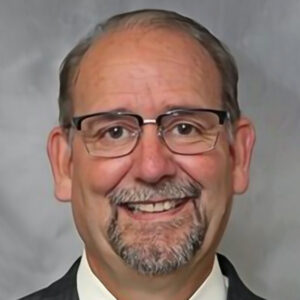 A man with glasses and a beard wearing a suit.